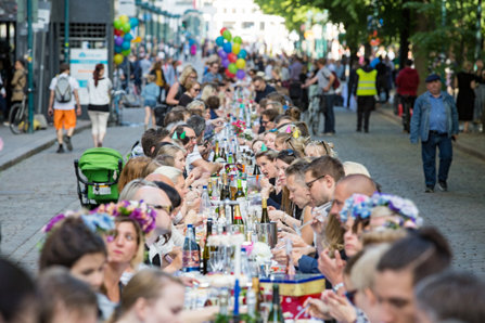Finland city celebration. People sitting at the long table drinking and eating.
