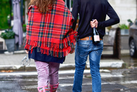 Couple by hand, hiding a bottle of wine
