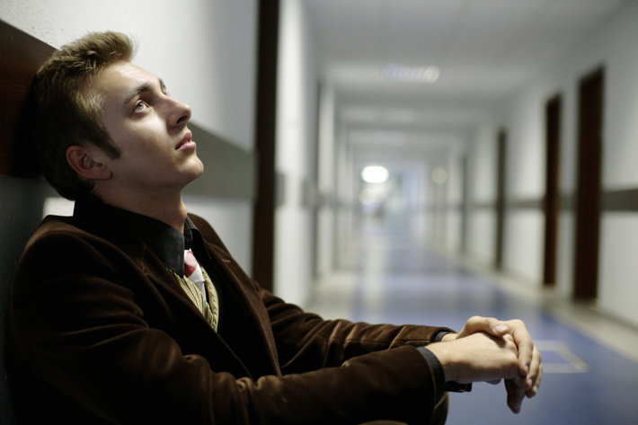 молодой человек сидит в коридоре в растерянности